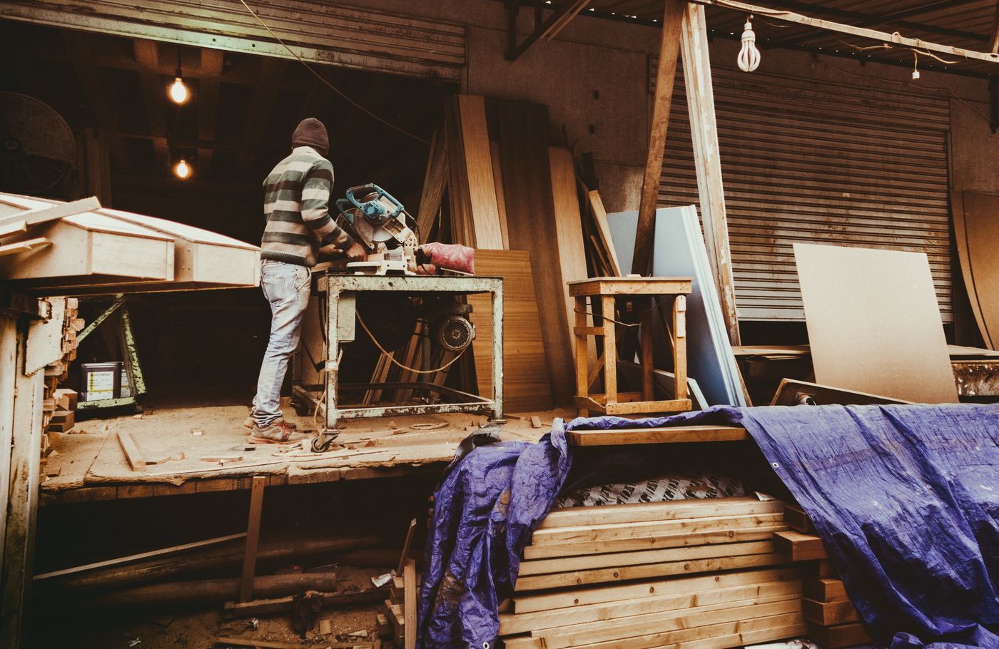 Werkplaats met een houtbewerker die aan houten balken werkt